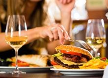 Phot of woman eating at table with wine and entrees