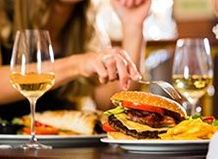 Phot of woman eating at table with wine and entrees
